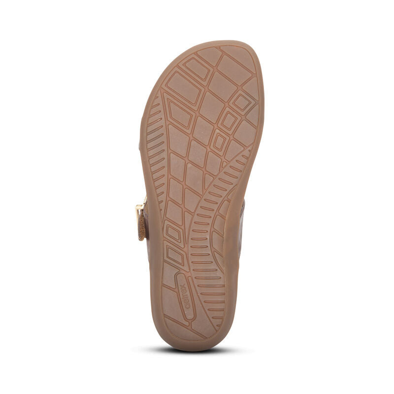 Bottom sole view of brown women's slip-on sandal with geometric traction pattern