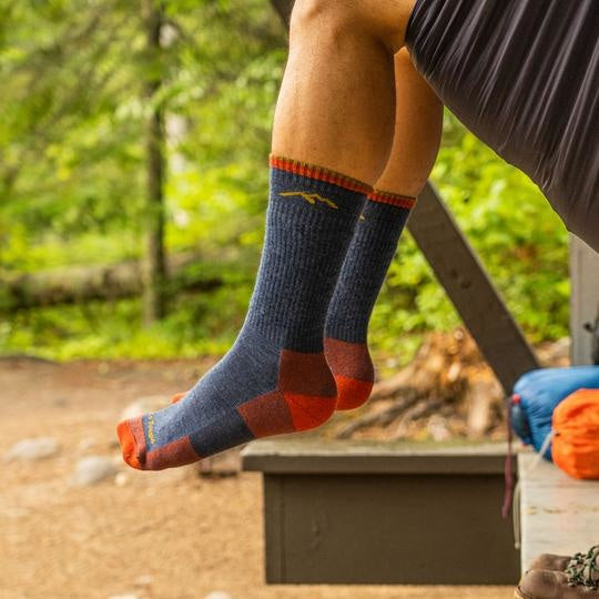 Darn Tough navy blue and red merino wool hiking boot socks worn at a campsite