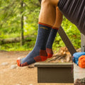 Darn Tough navy blue and red merino wool hiking boot socks worn at a campsite