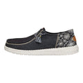 Hey Dude Wendy slip-on shoe in black denim with embroidered floral pattern and tassel detail