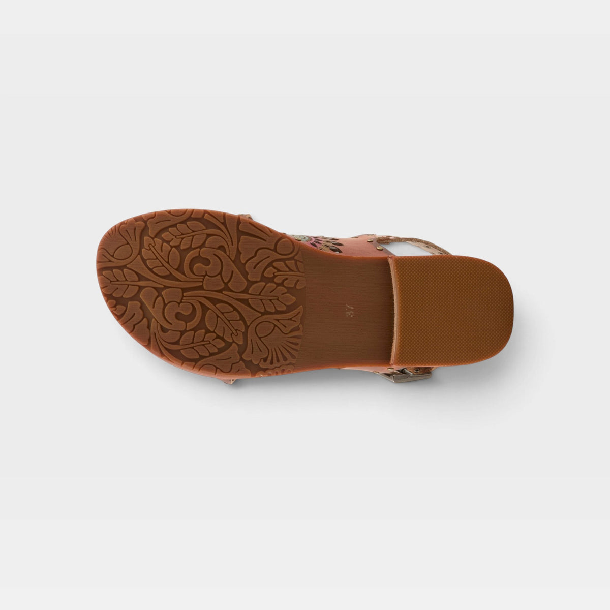 Bottom sole view of womens sandal with ornate floral embossed tread pattern and buckle straps