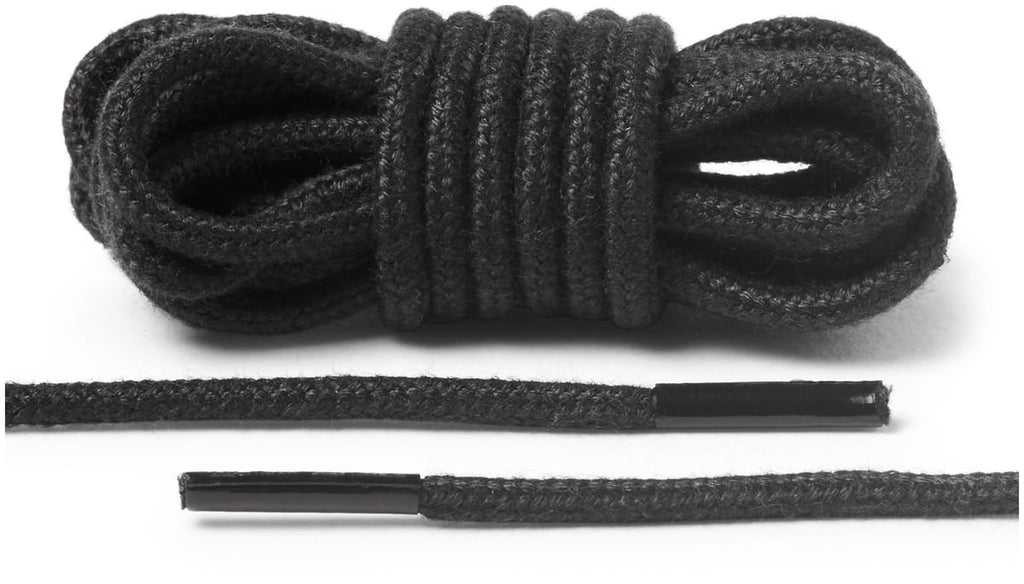 Black round braided shoelaces coiled in a bundle with two straight lace ends showing metal aglets
