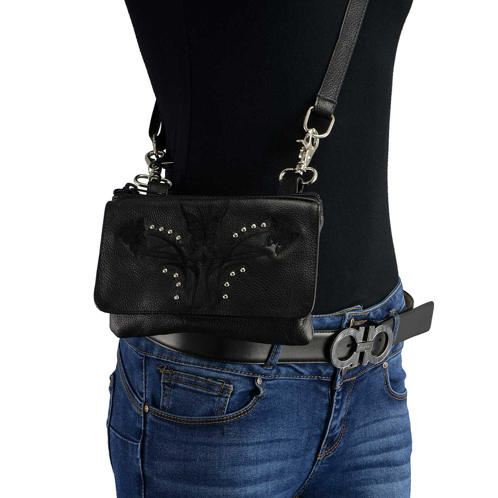 Black leather crossbody pouch with floral embossing and stud accents worn on body