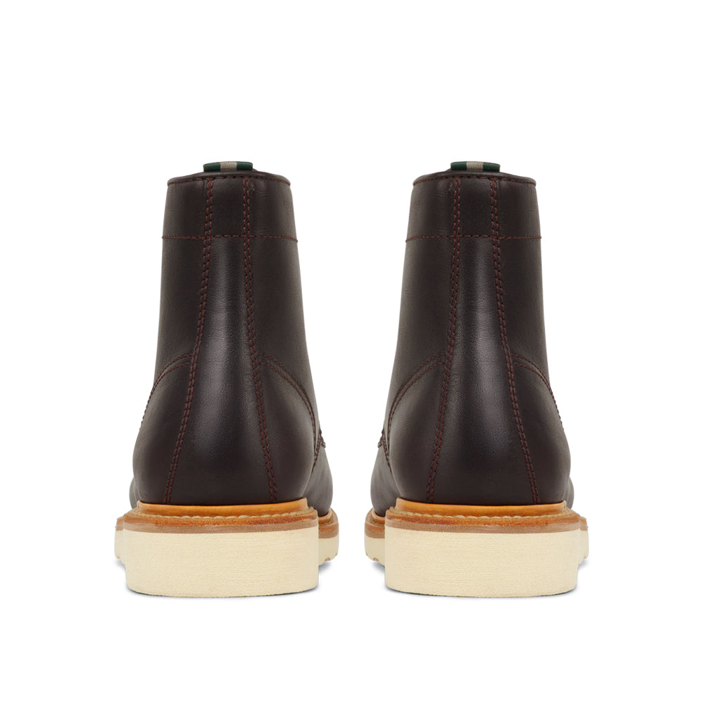 Rear view of men's leather cap toe boots with cream wedge sole and contrast stitching