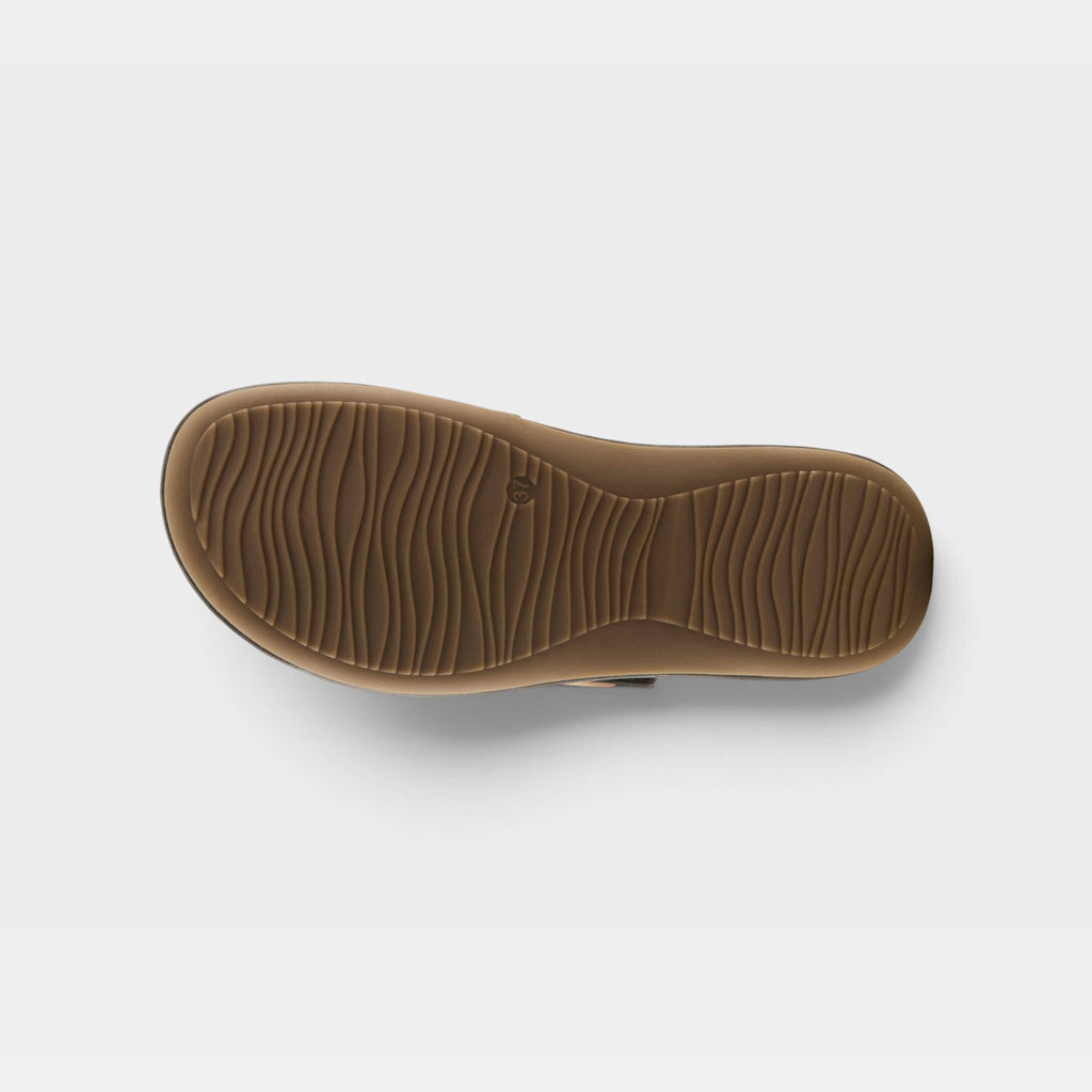 Bottom sole view of a womens sandal showing wavy textured tread pattern on tan rubber outsole
