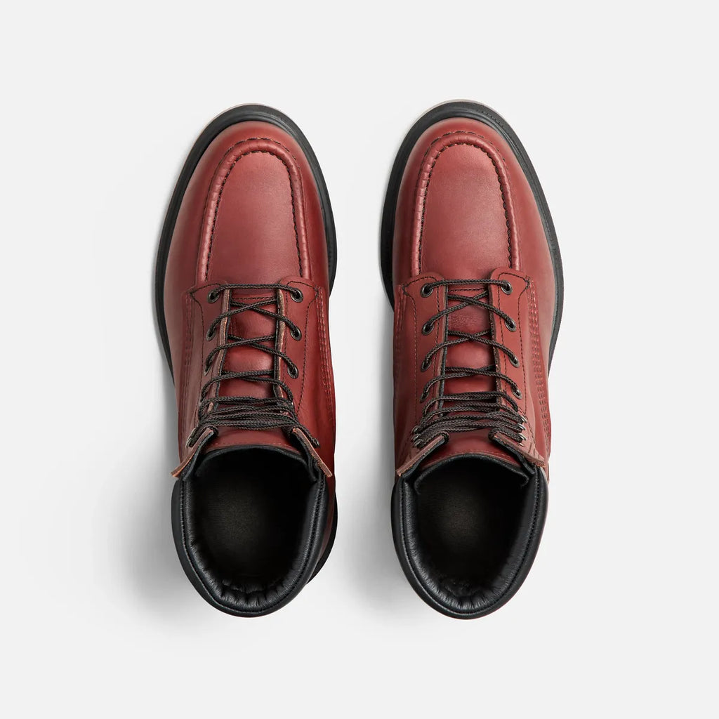 Top-down view of a pair of lace-up leather work boots with moc-toe stitching and black soles