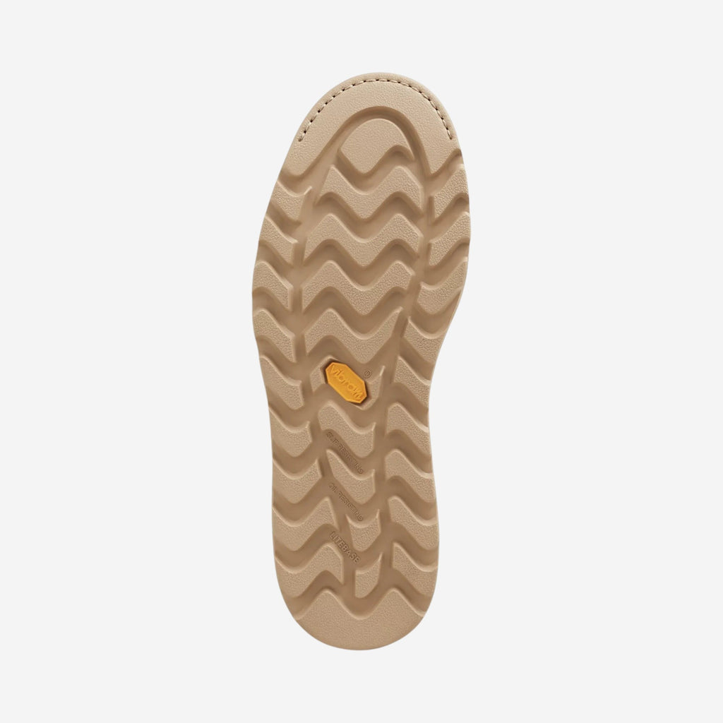 Bottom sole view of a tan work boot showing wavy traction tread pattern and Vibram logo