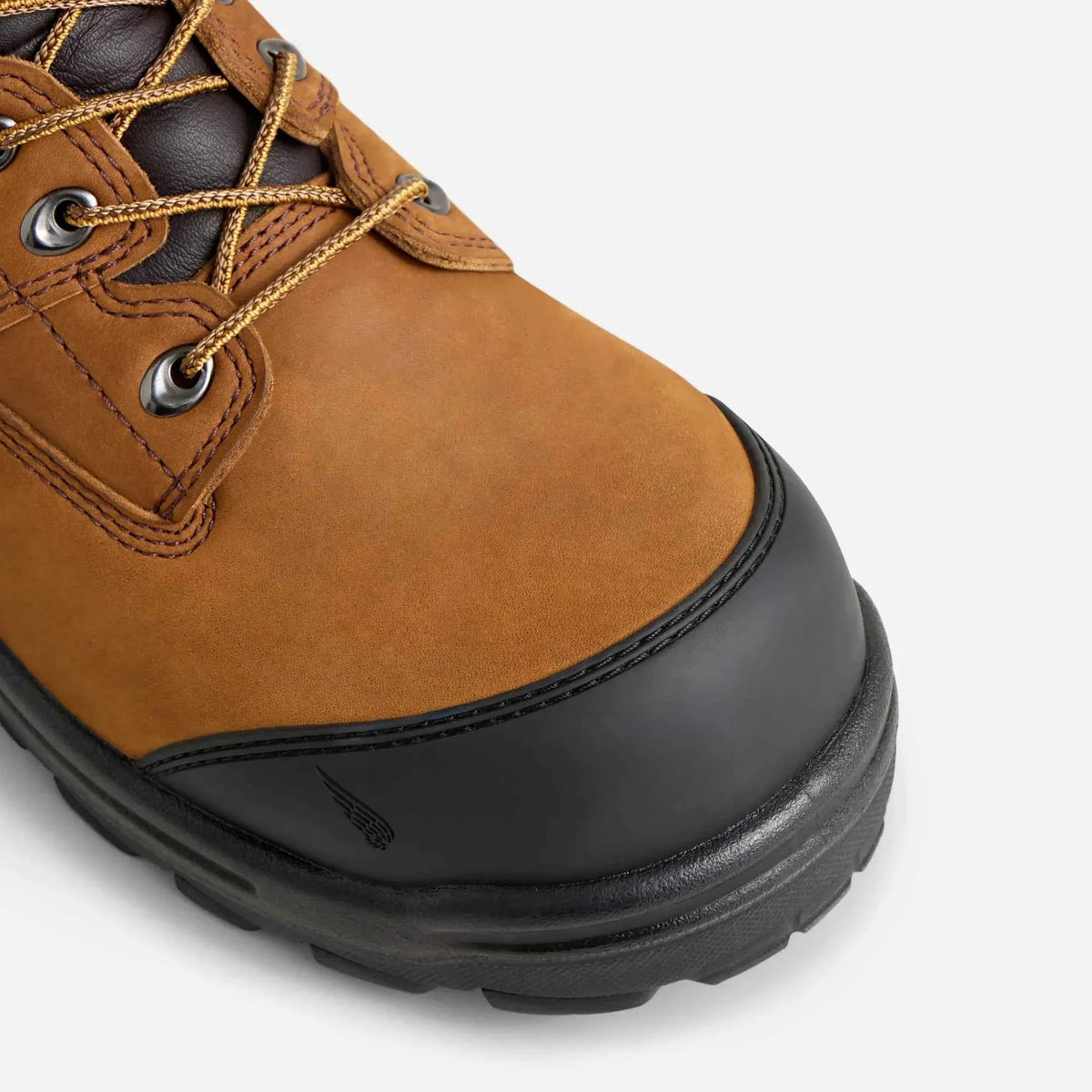 Close-up detail of a tan leather safety toe work boot with black rubber toe guard and lug sole