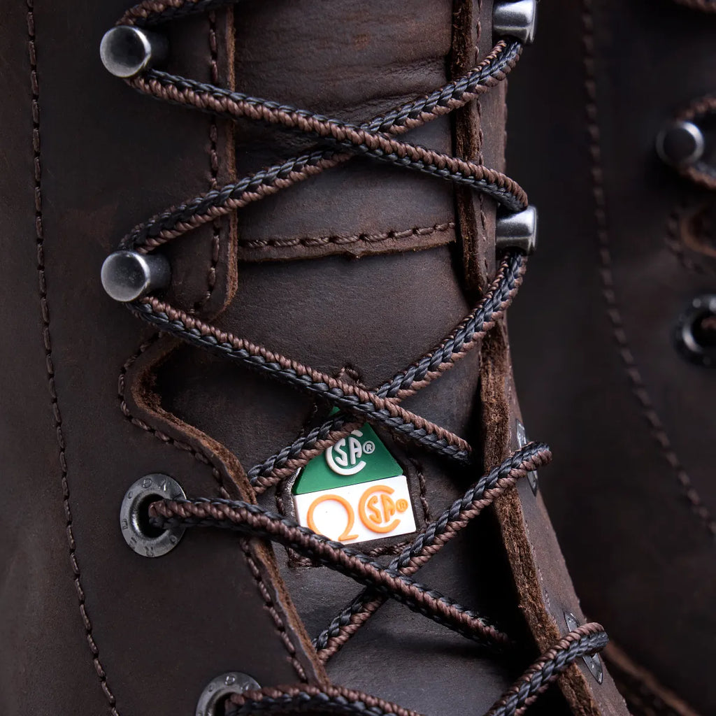 Close-up detail of dark brown leather work boot lacing with CSA safety certification tag