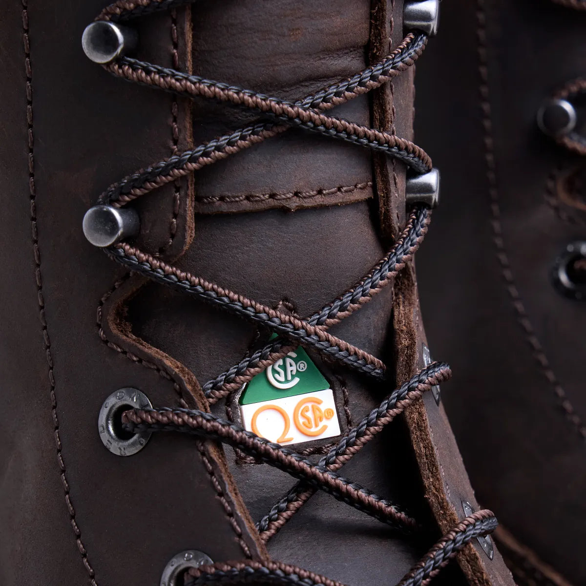 Close-up detail of dark brown leather work boot lacing with CSA safety certification tag