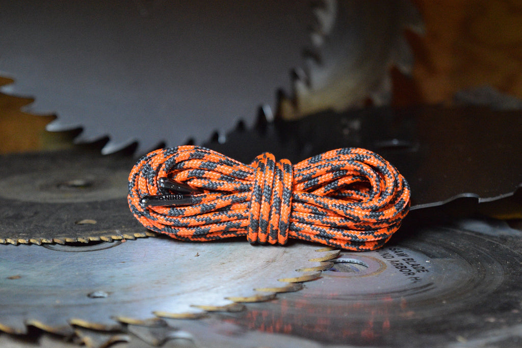 Coiled orange and black paracord shoelaces displayed on circular saw blades