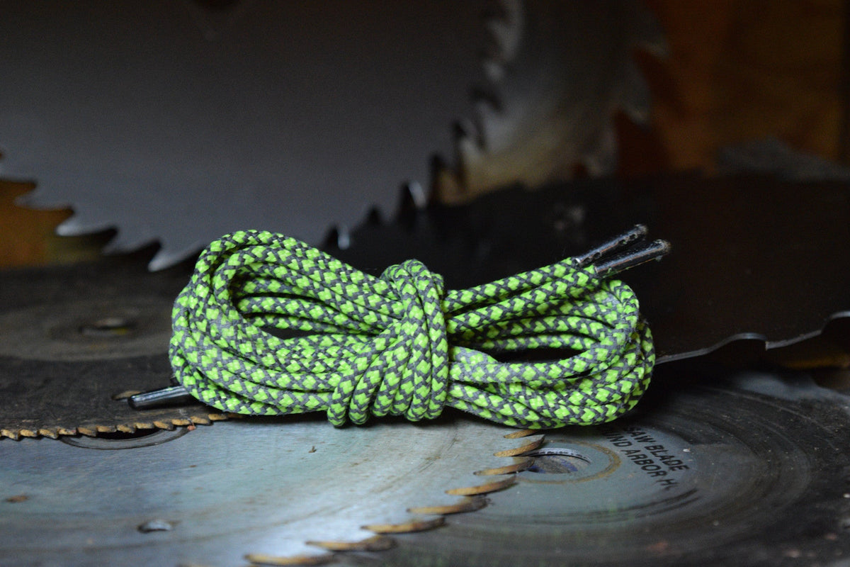 Green and black patterned round bootlaces coiled and knotted on a circular saw blade