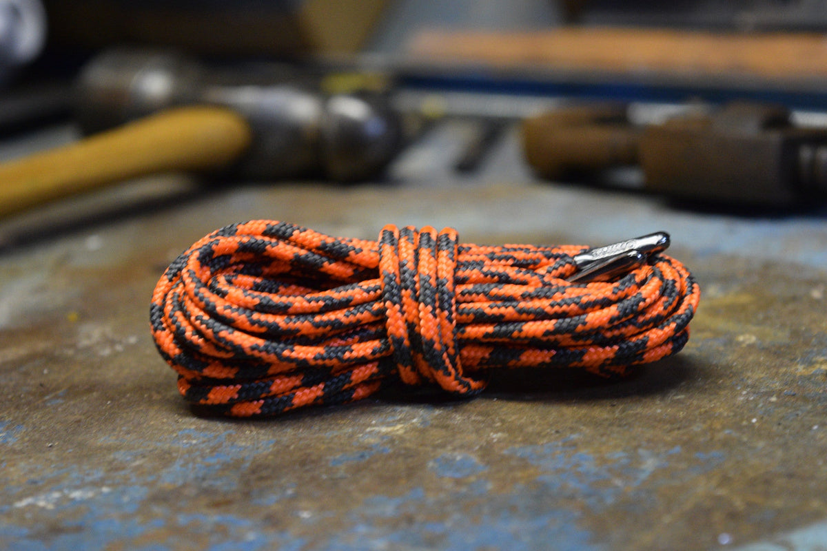 Coiled orange and black patterned round shoelaces with metal aglet on worn surface