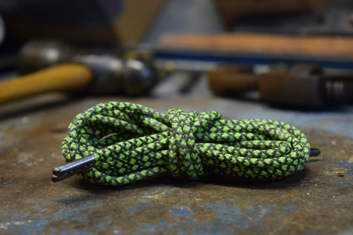 Rhino Laces coiled on a workbench surface with metal aglet tip visible