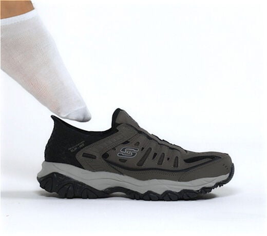 Skechers slip-on athletic shoe being worn with white sock on seamless background