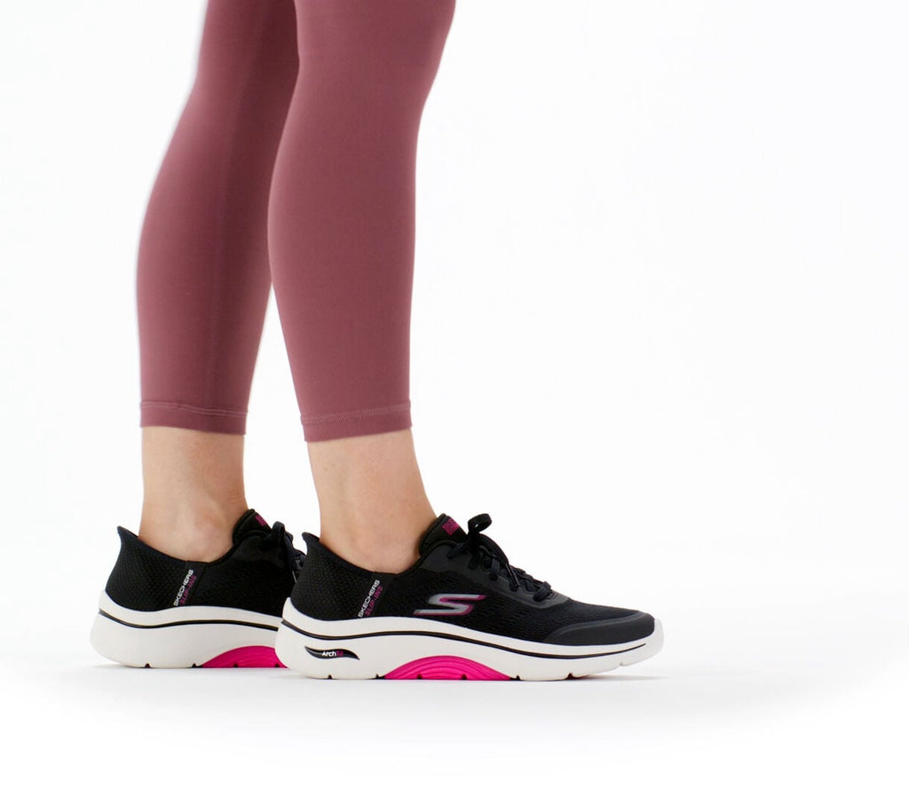 Woman wearing black and hot pink Skechers Go Walk sneakers with rose leggings, rear view