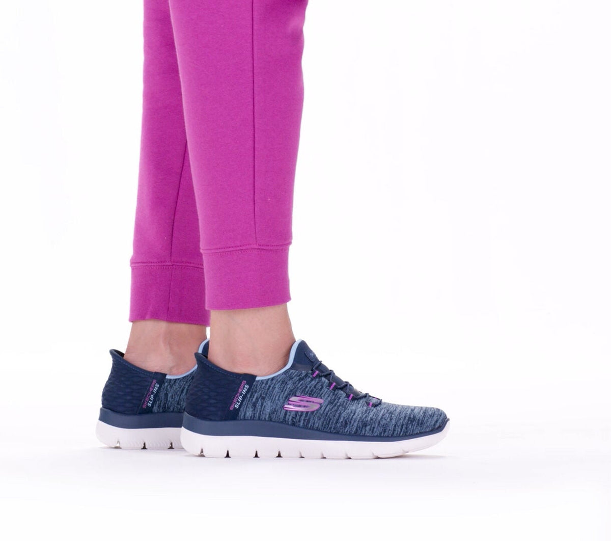 Woman wearing navy and purple Skechers Slip-Ins sneakers with pink jogger pants, rear view