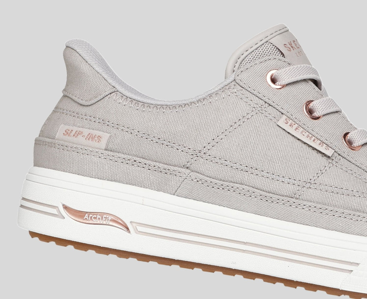 Close-up detail of Skechers Slip-ins Arch Fit canvas sneaker showing rose gold eyelets and branding