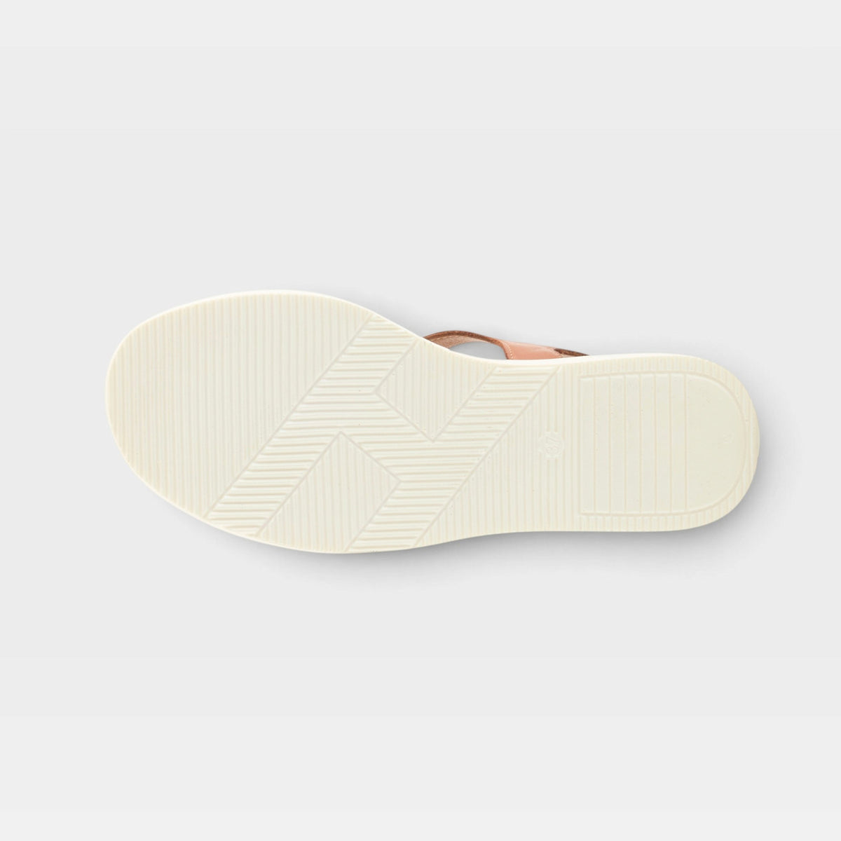 Bottom sole view of a women's sandal showing white textured outsole with chevron tread pattern