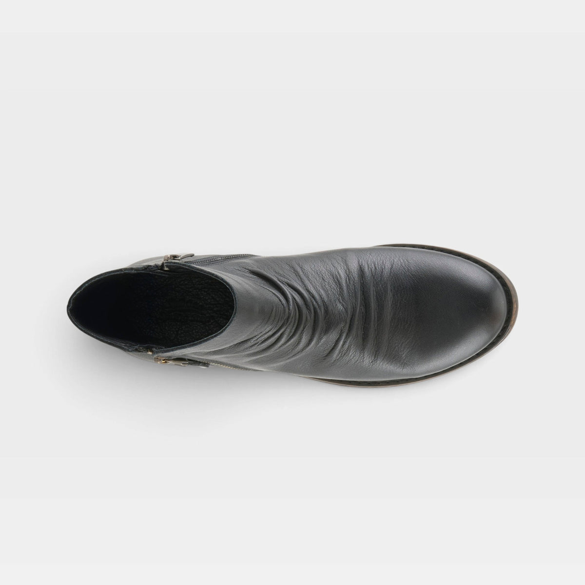 Top-down view of a black leather ankle boot with side zipper and buckle detail