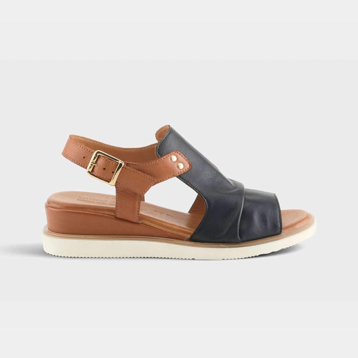 Women's wedge sandal with black leather upper, tan slingback strap, and gold buckle