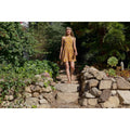 Woman wearing Taos Double U sandals walks down stone garden steps in sunlight